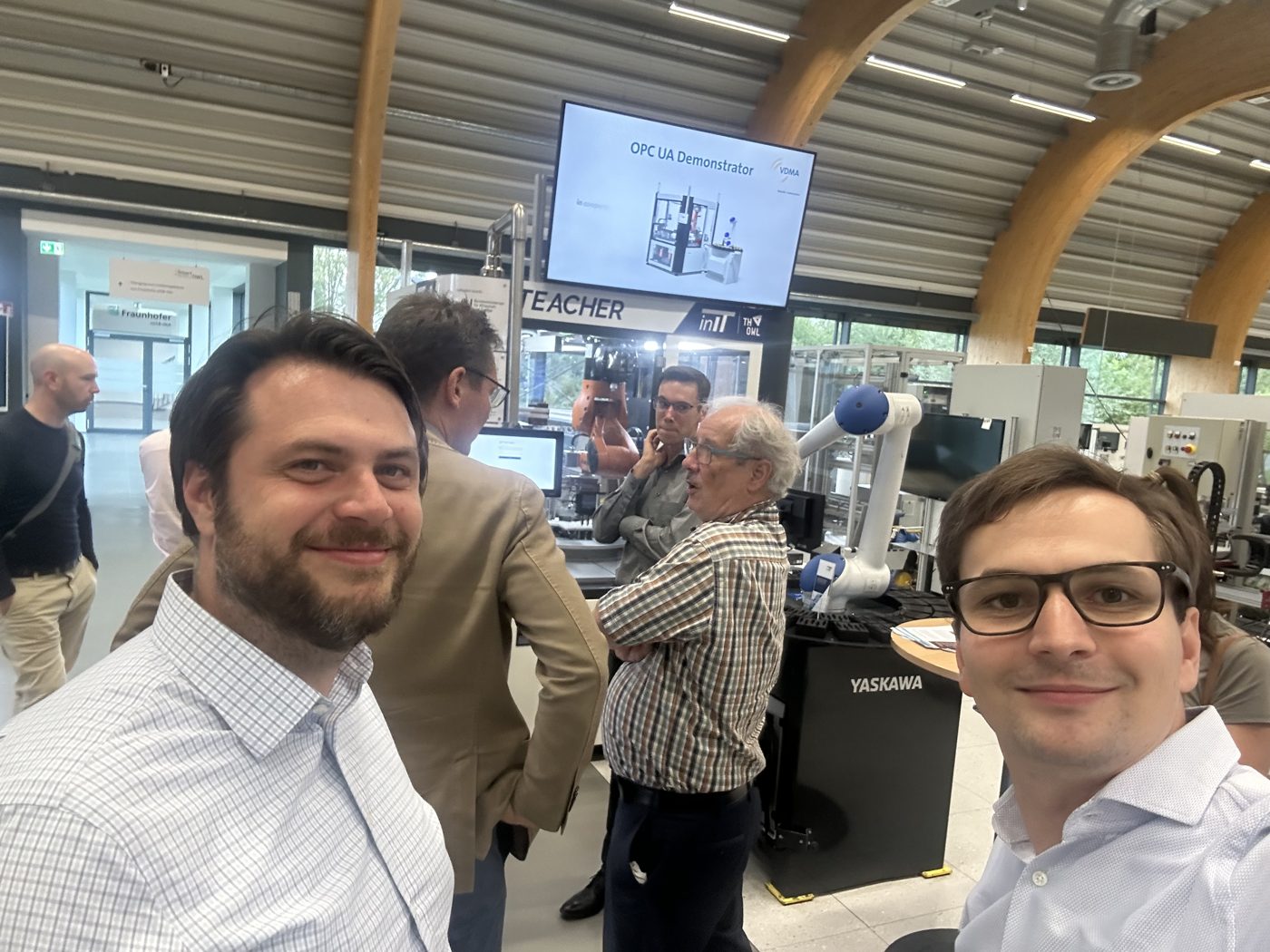 Zwei Teammitglieder bei einer Demonstration in einer Lernfabrik mit Industrierobotern